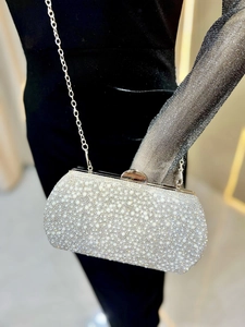 Detail of silver clutch bag featuring luxury white pearls and shimmering rhinestones