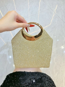 Nahaufnahme der goldenen Glitzer-Abendtasche mit rundem Metallgriff und Trapez-Struktur