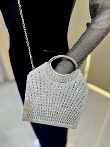 Silberne Abendtasche mit Strass und rundem Metallgriff am Arm eines schwarzen Kleides
