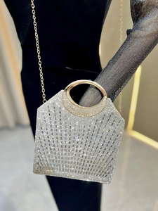 Detail der silbernen Strass-Abendtasche mit goldenem Rundgriff und glitzernden Steinen