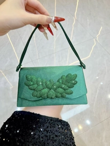Detail of green satin evening clutch with sparkling rhinestone leaf decoration and handle
