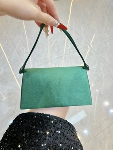 Detailed view of the green satin evening clutch bag with elegant glossy finish and handle