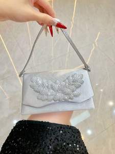Detail of elegant silver satin evening bag featuring intricate rhinestone floral embellishment