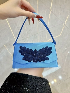 Detail view of sky blue satin evening bag featuring deep blue beaded leaf ornaments