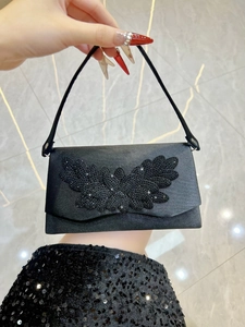 Detail of black satin evening bag featuring intricate rhinestone butterfly embellishments
