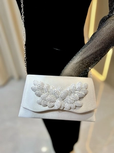 Detail of silver satin evening clutch with rhinestone leaf decoration and metal chain