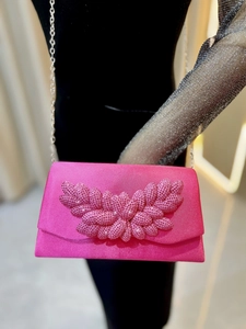 Detailed view of magenta satin evening clutch with pink rhinestone flower and silver chain