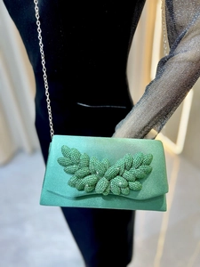 Detail of mint green evening clutch with sparkling rhinestone leaf design and silver chain