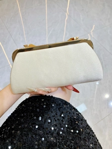 Detail of champagne gold satin evening clutch with elegant pleated texture and metal clasp