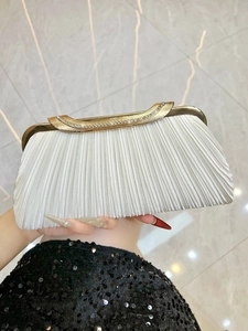 Close-up of white pleated evening bag with gold metal frame and rhinestone clasp