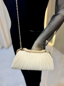 Detail of pleated satin evening clutch with sparkling rhinestones and gold chain