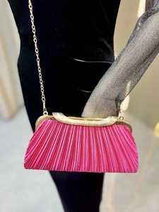 Detail of rose red pleated satin clutch bag with gold rhinestone trim and chain strap