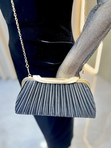 Close-up of pleated evening clutch with sparkling rhinestones and gold chain strap