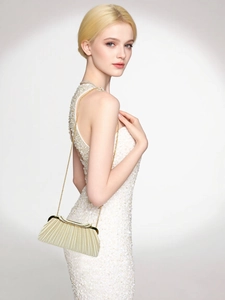 Detail of elegant pleated evening clutch bag with golden chain strap on a model