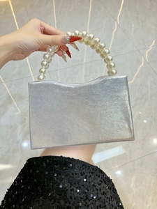 Detail of silver evening clutch bag with sparkling fabric and large pearl handle