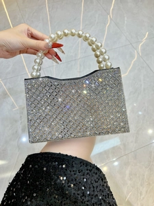 Detailed close-up of a luxury evening handbag with silver rhinestones and pearl handle