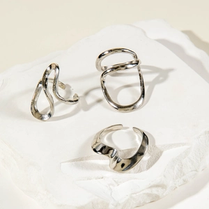 Three-piece silver minimalist irregular ring set shown on textured stone background