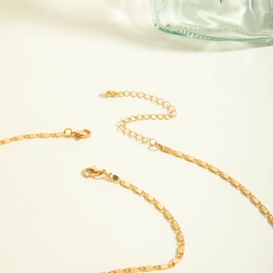 Détail du collier doré avec fermoir mousqueton, chaîne d'extension et petite boule
