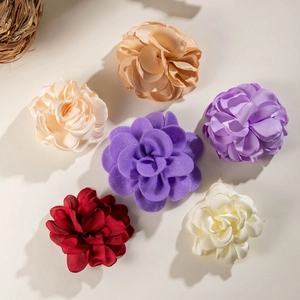 Detail of colorful fabric camellia flower hair clips in champagne, purple, and burgundy