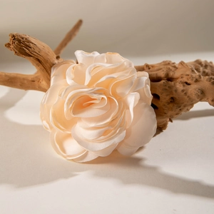 Champagne fabric rose hair clip made of satin, displayed on an elegant driftwood branch