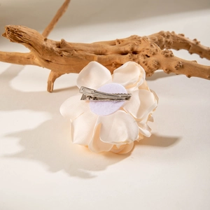 Elegant cream fabric camellia flower hair clip on a natural wood branch