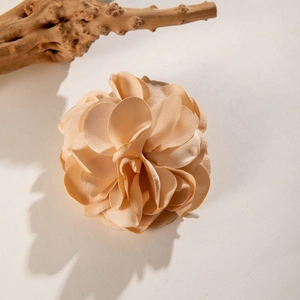 Macro detail of champagne satin flower hair clip with multi-layered fabric petals