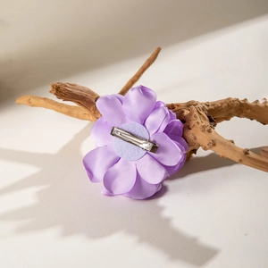 Detail of purple satin fabric flower hair clip with silver metal duckbill clip back