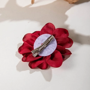 Detail view of red fabric camellia flower hair clip with silver metal duckbill base