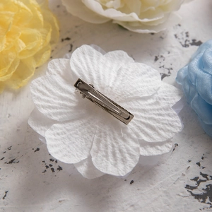 Detail of white fabric flower hair clip with silver metal alligator clip on back