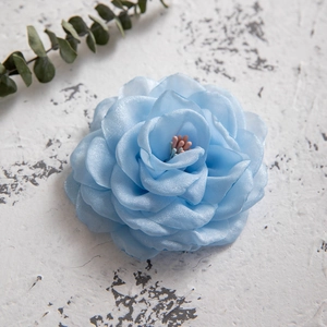Detail of blue fabric camellia hair clip with delicate petals and colorful stamens