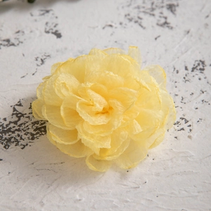 Detailed close-up of yellow fabric camellia hair clip made of sheer organza petals