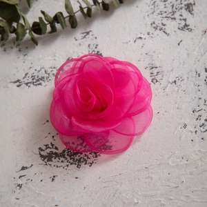 Detail shot of a bright dark pink organza fabric rose clip on a vintage background