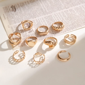 Detail shot of a 10-piece gold twist and hollow ring set on vintage script background