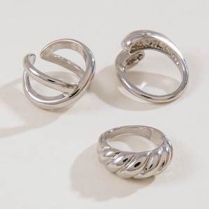 Flat lay of silver twisted and crossover rings showing polished texture and punk style