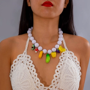 Close-up of bohemian beaded necklace with white pearls and colorful vegetable pendants