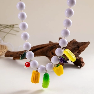 Detail of bohemian necklace with white beads and realistic mixed fruit and vegetable charms