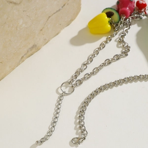 Detail of silver chain necklace with cute avocado and strawberry fruit pendants