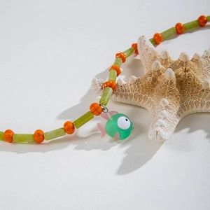 Close-up of bohemian avocado green beaded necklace with cute fish pendant and starfish