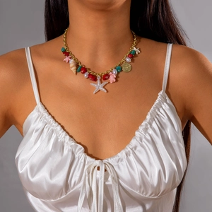 Detail of bohemian necklace with sea star, beads, and shells on a model in white satin