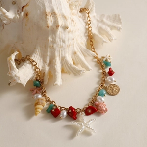 Detail of bohemian gold chain necklace with white starfish and colorful charms on seashell