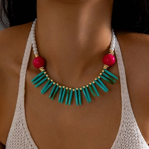 Détail d'un collier bohème avec perles blanches et charms roses porté par un mannequin