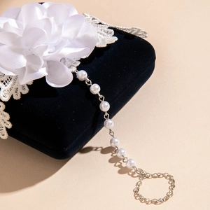 Detailed view of 3D orchid flower hand chain with white pearls on black jewelry box