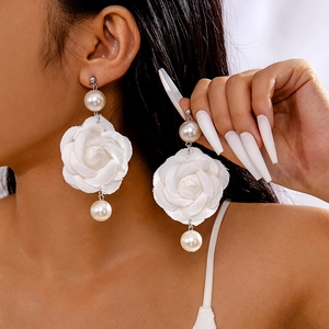 Détail de grandes boucles d'oreilles rose en tissu et perles nacrées blanches