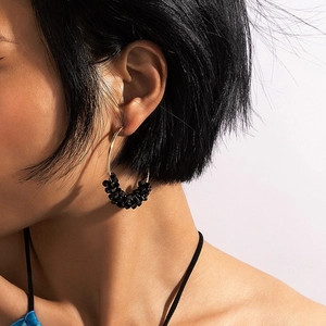 Gros plan de créoles dorées avec perles noires portées par un mannequin style chic