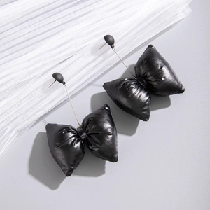Détail de boucles d'oreilles nœud noir tendance avec une texture bouffante effet cuir