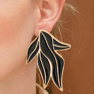 Détail d'une grande boucle d'oreille feuille en émail noir avec bords en métal doré