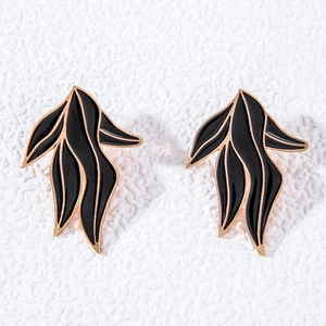 Détail de boucles d'oreilles en émail noir avec placage or et design artistique