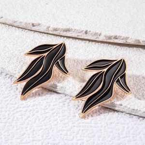 Gros plan détaillé de boucles d'oreilles en forme de feuille noires et dorées sur pierre