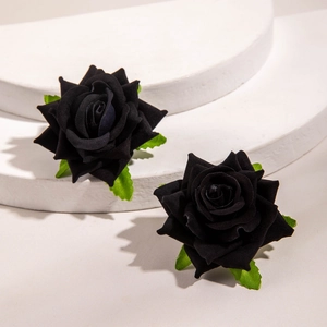 Détail de boucles d'oreilles rose en tissu noir fait main avec des feuilles vertes