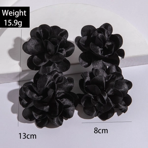 Macro shot of 4-piece black fabric flower earrings with satin texture on white stones